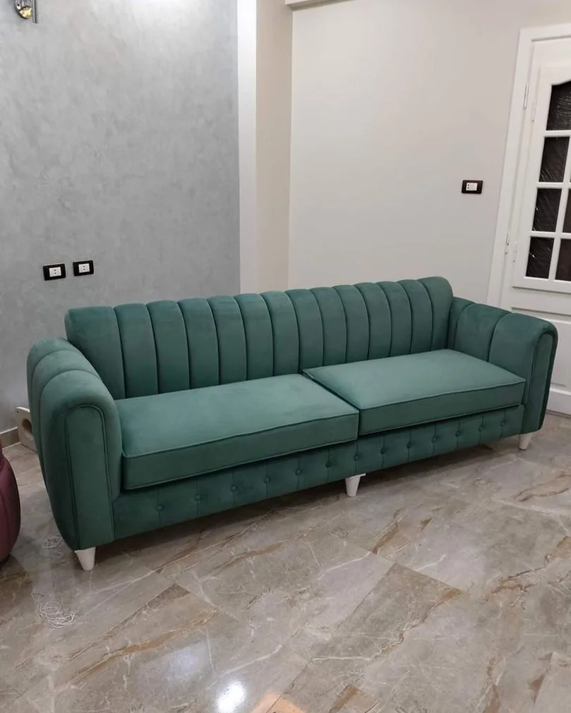 Green velvet chesterfield sofa with a buttoned back and brass studs.