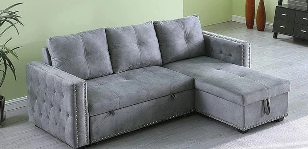 Grey buttoned sofa-cum-bed with a chaise, closed and arranged as a sofa.