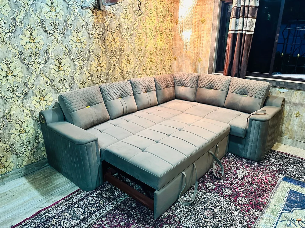 Cream corner sofa-cum-bed opened out in a carpeted room.
